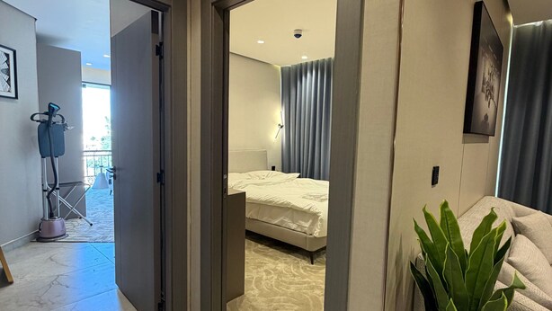 Quarto de hotel moderno com uma cama, uma planta em vaso e vista para a varanda.