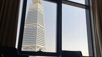 A room with a large window, two chairs, and a view of a tall building.