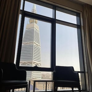 A room with a large window, two chairs, and a view of a tall building. - RIO OLAYA HOTEL  (Riyadh)
