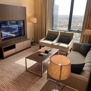 A modern hotel room with a large TV, two sofas, a coffee table, and a view of the city. - RIO OLAYA HOTEL  (Riyadh)