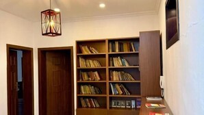 A hallway with a wooden bookshelf, a tiled floor, and a hanging light fixture. - Hotel La Cita (Tirana)