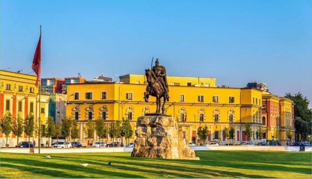 A statue in a square with a building in the background.
