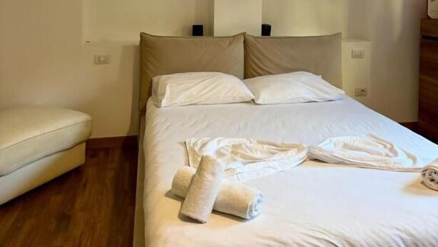 A hotel room with a bed, a chair, and an air conditioning unit. - Hotel La Cita (Tirana)