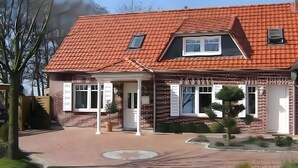 A two-story house with a red-tiled roof, a covered porch, and a brick facade.