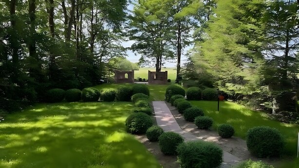 A garden with a paved path, neatly trimmed bushes, and a brick structure.