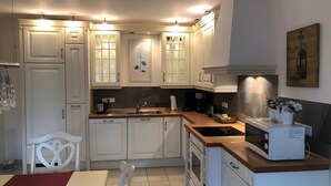 A kitchen with white cabinets, a wooden countertop, a microwave, and a sink.