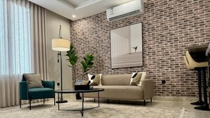 A modern living room with a brick wall, a sofa, a coffee table, a lamp, and a plant. - Khozama Living (Jeddah)