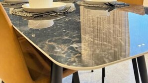 A modern dining area with a marble table, white plates, and orange chairs. - Khozama Living (Jeddah)