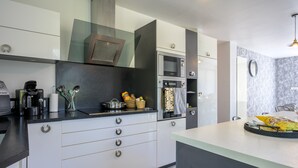 A modern kitchen with a microwave, oven, and coffee maker. - La Maison du Portier: Mountain View, Private Terrace with Fire Pit and Wi-Fi (Malmerspach)