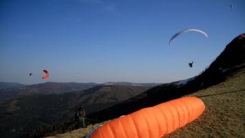 Een bergachtig landschap met meerdere paragliders in de lucht.