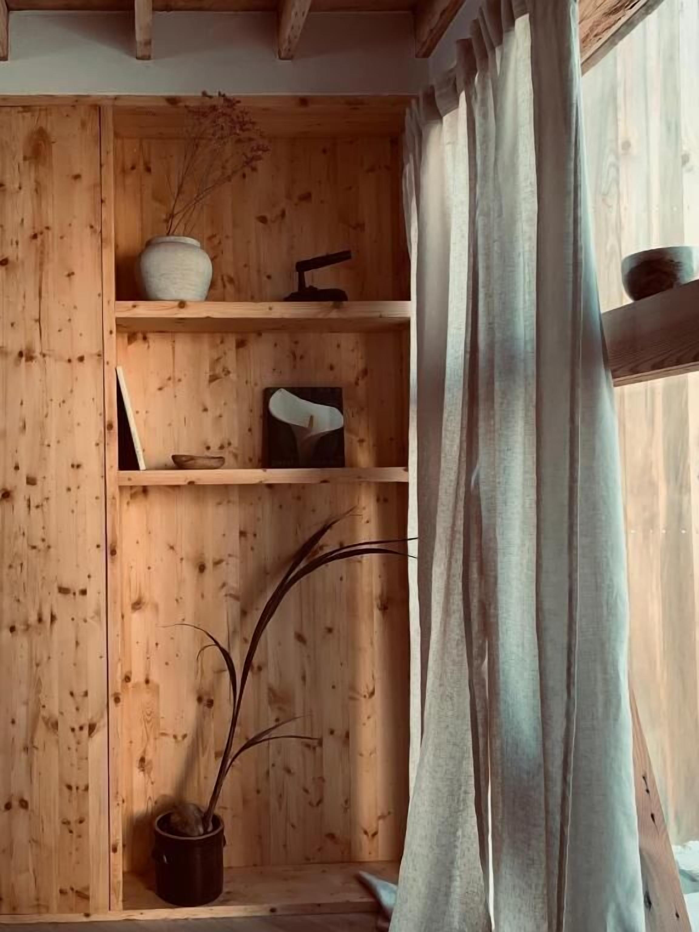Puisesti sisustettu tila, jossa on hyllyjä, maljakko, kulho ja ruukussa oleva kasvi.
