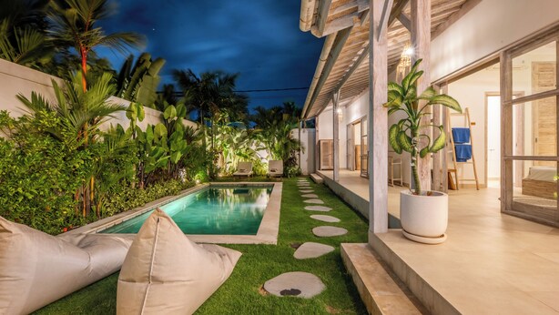 A pool with a stone pathway, a grassy area, and a potted plant. - New Villa Misha Modern 2BR Pool with Tropical Garden Near Seminyak (Badung)