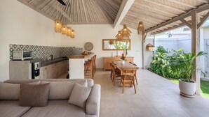 A modern kitchen with a dining area, a ceiling fan, and a potted plant. - New Villa Misha Modern 2BR Pool with Tropical Garden Near Seminyak (Badung)