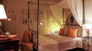 A four-poster bed with a canopy, framed artwork on the walls, and a bedside table with a lamp. - Elegant apartment in the center of Turin. (Torino)