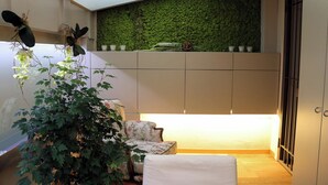 A room with a green wall, a plant, a sofa, and a bed. - Elegant apartment in the center of Turin. (Torino)