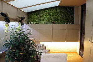 Ein Zimmer mit grüner Wand, einer Pflanze, einem Sofa und einem Bett.