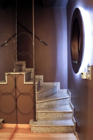 Eine Treppe mit einem runden Spiegel und einer Wandleuchte.