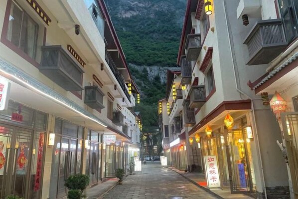 Una calle estrecha flanqueada por edificios, algunos con balcones y carteles.