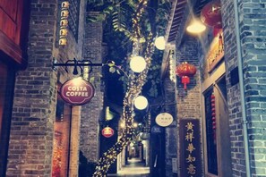 Un callejón interior con luces colgantes, un letrero de cafetería y paredes de ladrillo.
