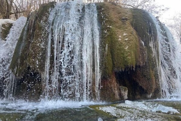 A waterfall cascading over a moss-covered rock formation.