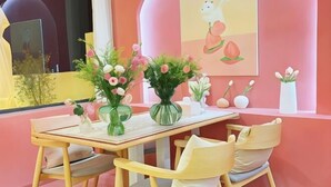 Un comedor con una mesa, sillas y centros de mesa florales.