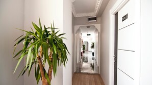 Een gang met een plant, een deur met een nummer en een trap die naar een andere kamer leidt.