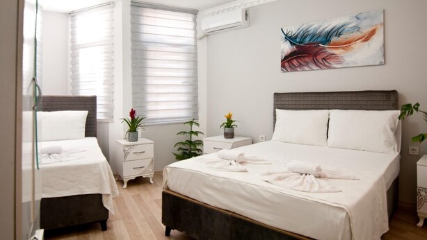 Hotelkamer met een groot bed, twee nachtkastjes, een raam met jaloezieën, een wandairconditioner en een schilderij.