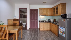 Eine kleine Küche mit Holzausstattung, einem Kühlschrank und einer Mikrowelle.