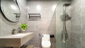 Un baño moderno con inodoro, lavamanos, espejo y ducha.