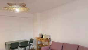 A room with a wooden dining table, two chairs, a sofa, a small wooden side table with a toaster, and a hanging light fixture. - La Garde, Refurbished - ideal location, sleeps 8 (La Garde)