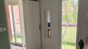 A room with a wooden floor, a sliding glass door, a small table, and a chair. - La Garde, Refurbished - ideal location, sleeps 8 (La Garde)