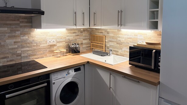 A compact kitchen with a built-in washer, a microwave, and a wooden countertop. - La Garde, Refurbished - ideal location, sleeps 8 (La Garde)