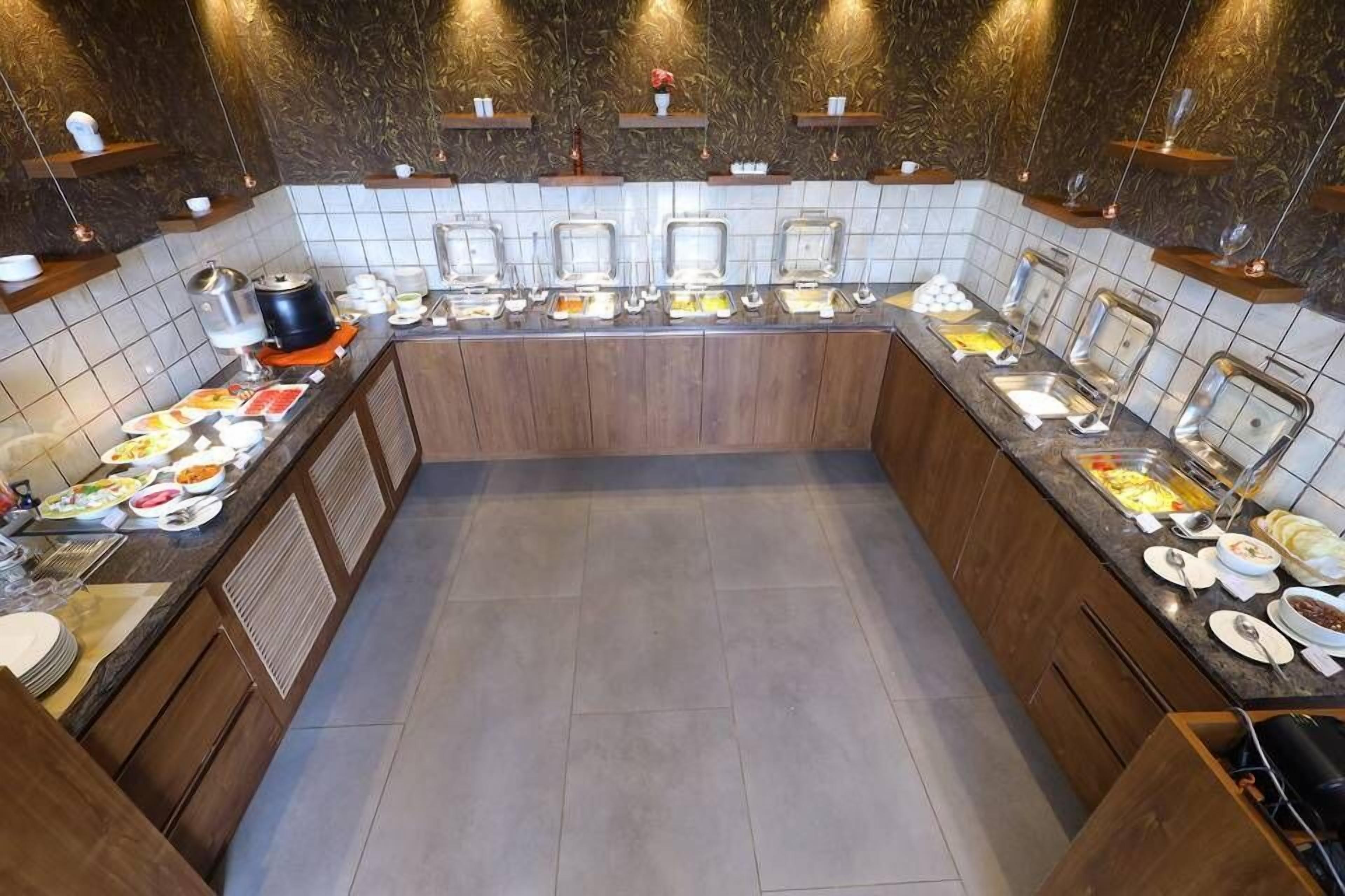 A buffet setup with multiple food stations, a tiled backsplash, and wooden cabinets.