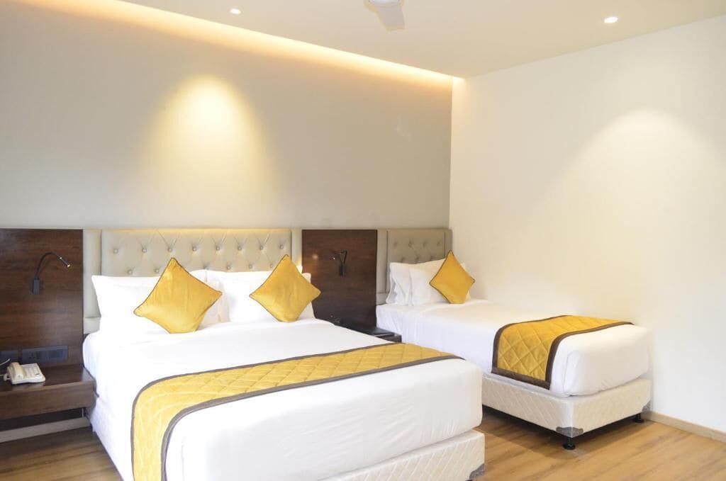 A hotel room with two beds, a wooden headboard, and a bedside table with a phone.