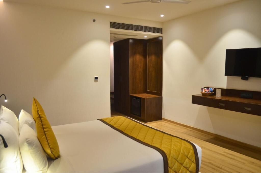 A hotel room with a bed, a TV mounted on the wall, and a wardrobe.