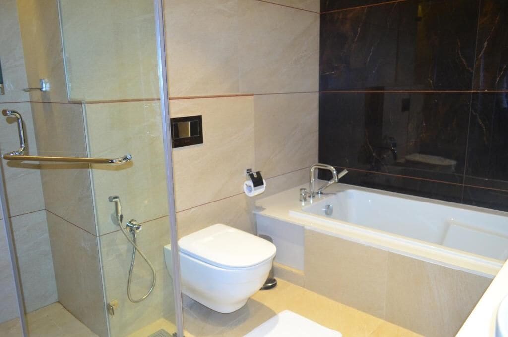 A bathroom with a glass shower enclosure, a toilet, and a bathtub.