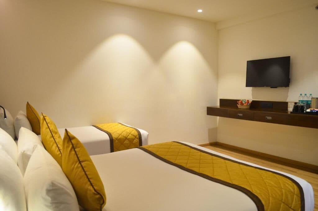 Ett hotellrum med två sängar, en platt-TV som är monterad på väggen och en minibar.