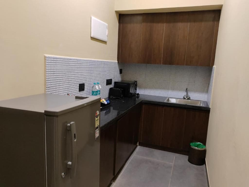 Una cocina compacta con refrigerador, lavamanos y microondas.