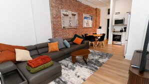 Een moderne woonkamer met een bank, salontafel en een eethoek met stoelen.