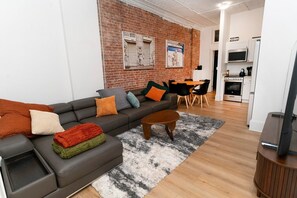 A modern living room with a sofa, coffee table, and a dining area with chairs. - Chic 3BR in Flatiron/Chelsea | W/D + Smart TV’s (New York)