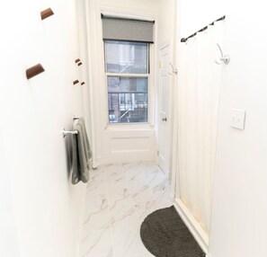 A bathroom with a window, a towel rack, a shower curtain rod, and a marble floor. - Chic 3BR in Flatiron/Chelsea | W/D + Smart TV’s (New York)