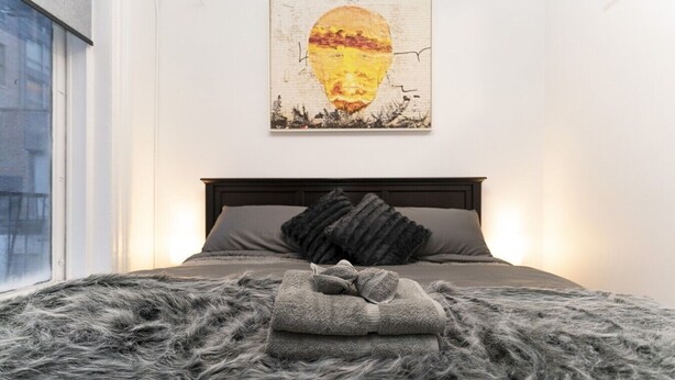 Een slaapkamer met een bed, een raam en een schilderij aan de muur.