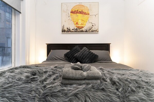 A bedroom with a bed, a window, and a painting on the wall. - Chic 3BR in Flatiron/Chelsea | W/D + Smart TV’s (New York)