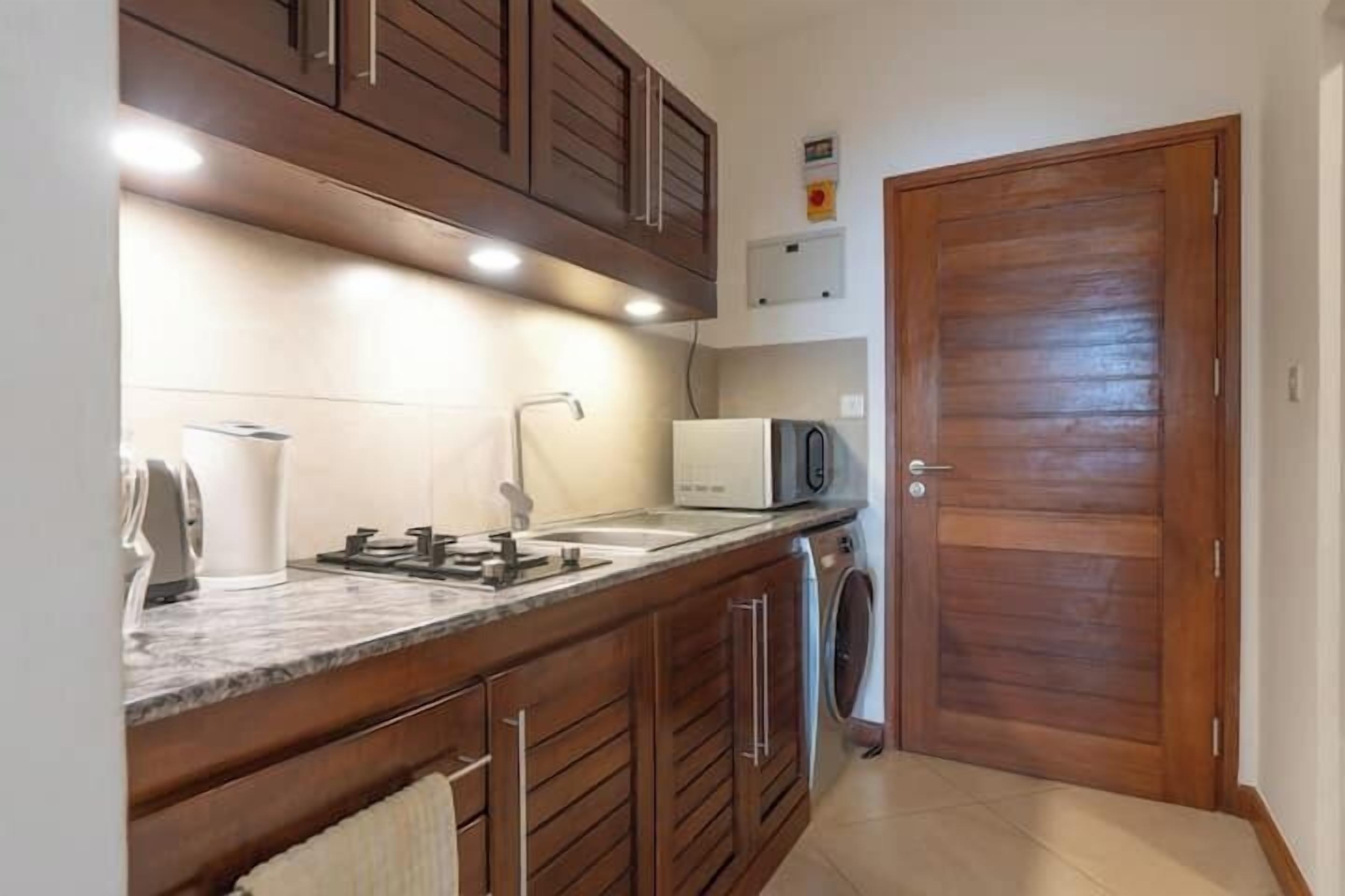 A kitchen with wooden cabinets, a built-in microwave, and a washing machine.