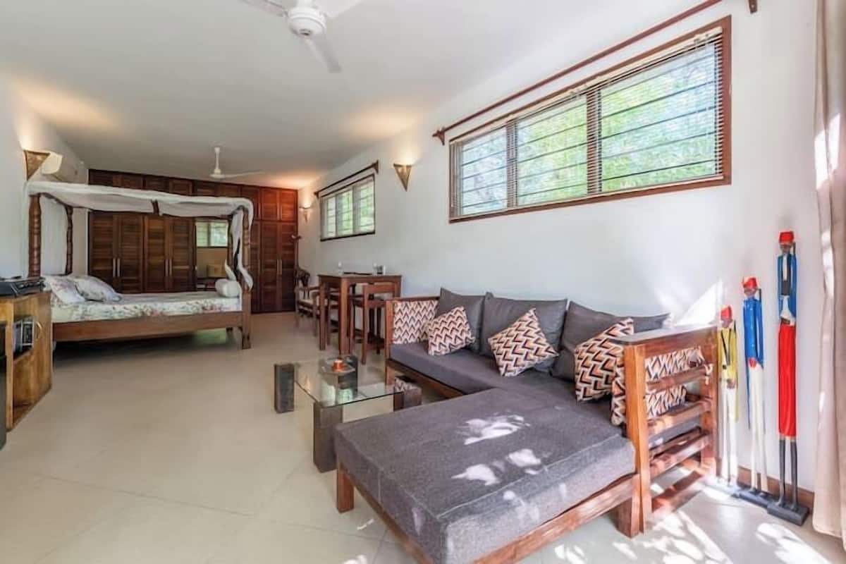 Una habitación con cama, sofá y una pequeña mesa.
