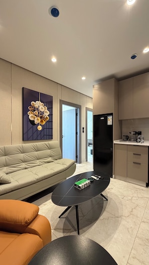 A modern living room with a sofa, a coffee table, and a kitchen area with cabinets and appliances. - 205 Tara-jre Jabal Al Lweibdeh With Stunning View (Amman)