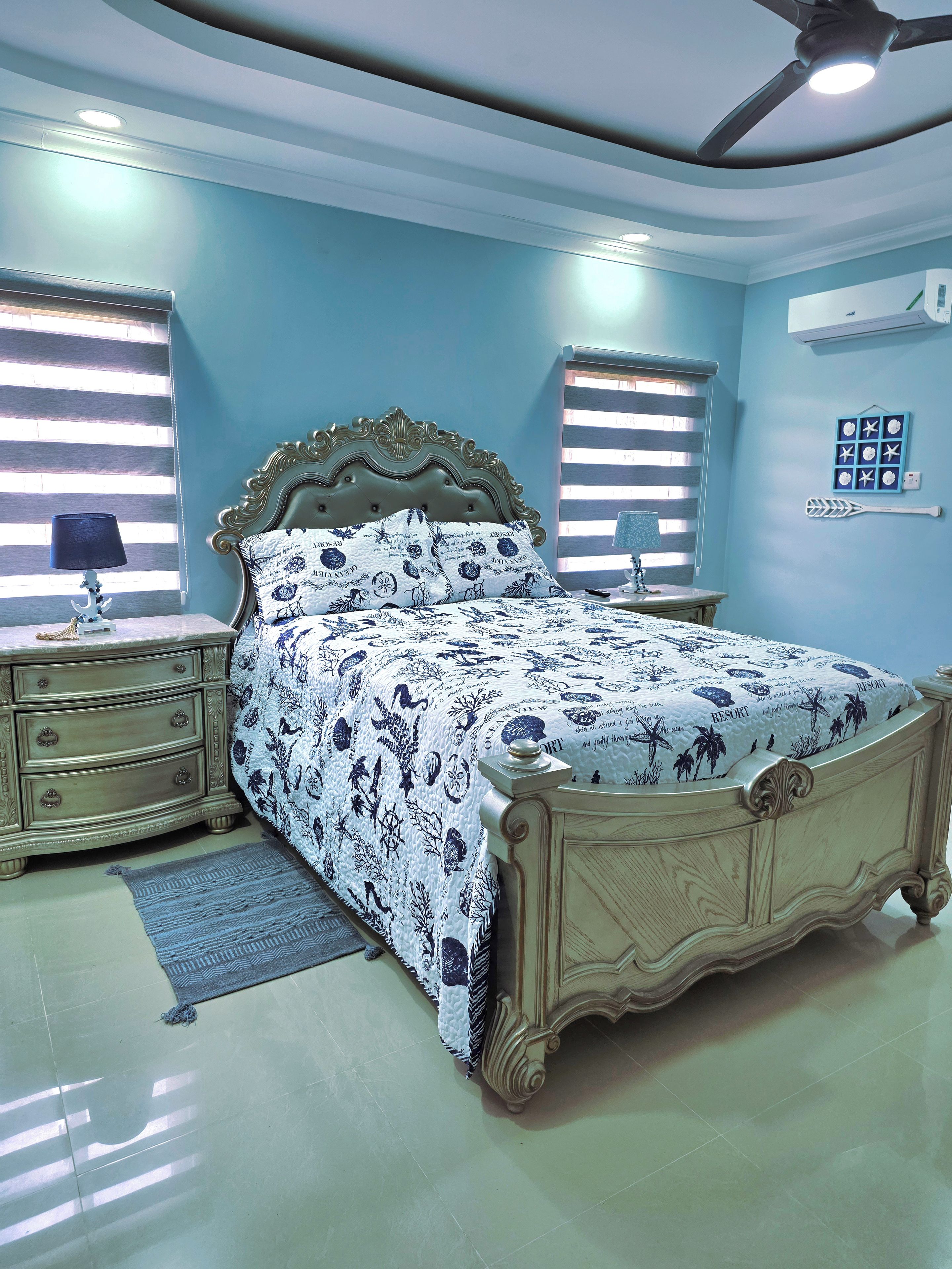 Quarto com cama, mesas de cabeceira, cômoda e ventilador de teto.