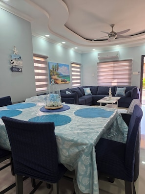 A modern living room with a dining area, featuring a ceiling fan, a painting of a beach, and a sign on the wall. - 2-bedroom bungalow in beautiful Ocho Rios gated community  with AC. (Ocho Rios)