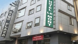 A multi-story building with signs for 'King Plaza' and 'Hotel Le Mont.' - Hotel Le Mount (New Delhi)