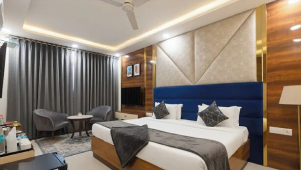 A modern hotel room with a large bed, a desk, a chair, and a ceiling fan. - Hotel Le Mount (New Delhi)